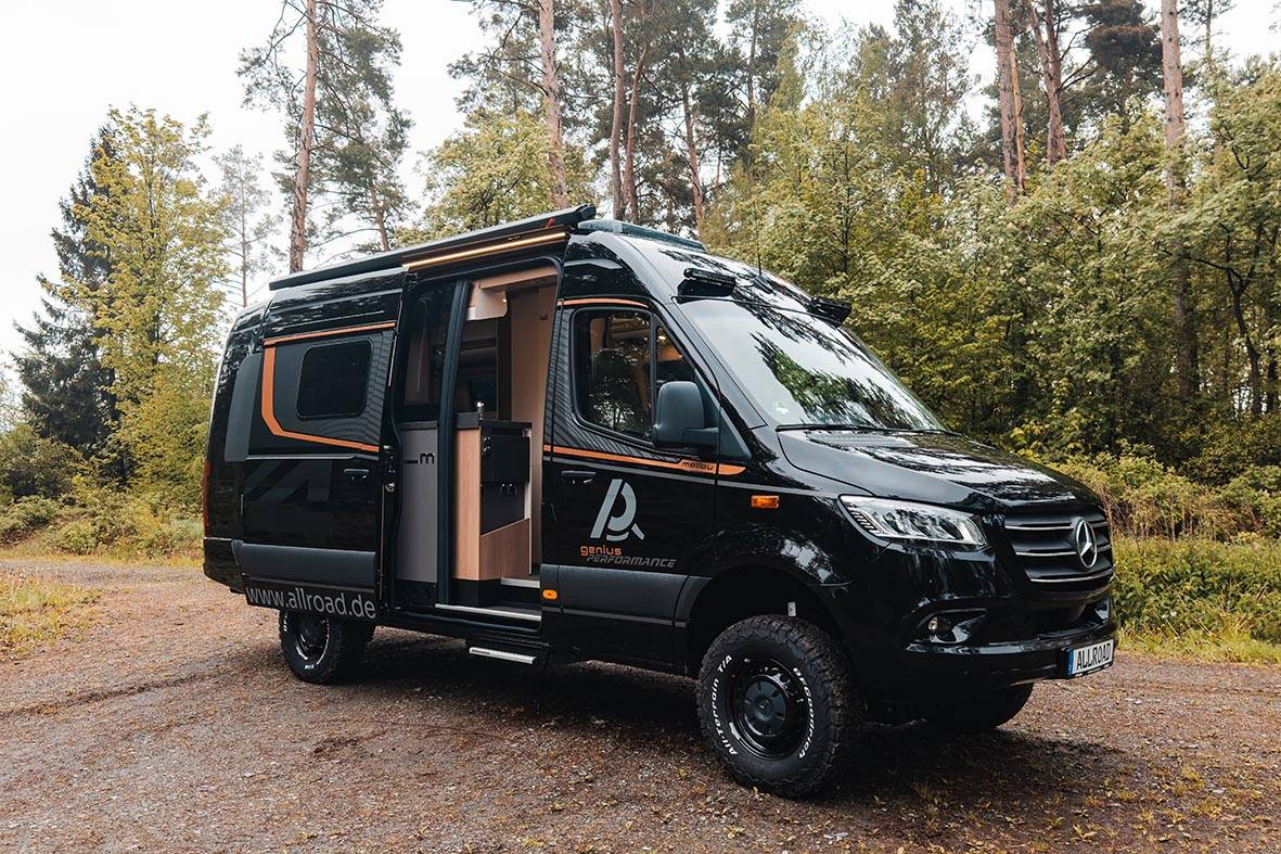 Malibu Genius Performance 4x4 von AllRoad in schwarzer Außenansicht auf Waldweg mit geöffneter Schiebetür.