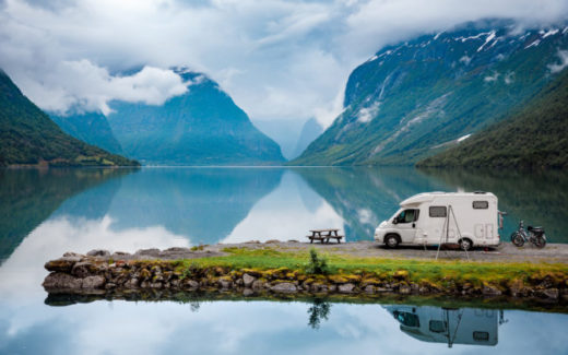 Teilintegriertes Wohnmobil auf einer Landzunge im See vor Berglandschaft