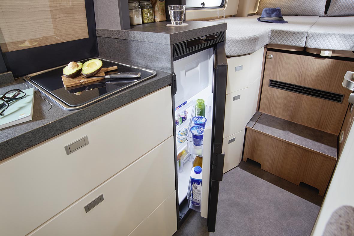 Geöffneter Kühlschrank in der Küchenzeile des Malibu Genius 4x4 mit Blick zum Schlafbereich.