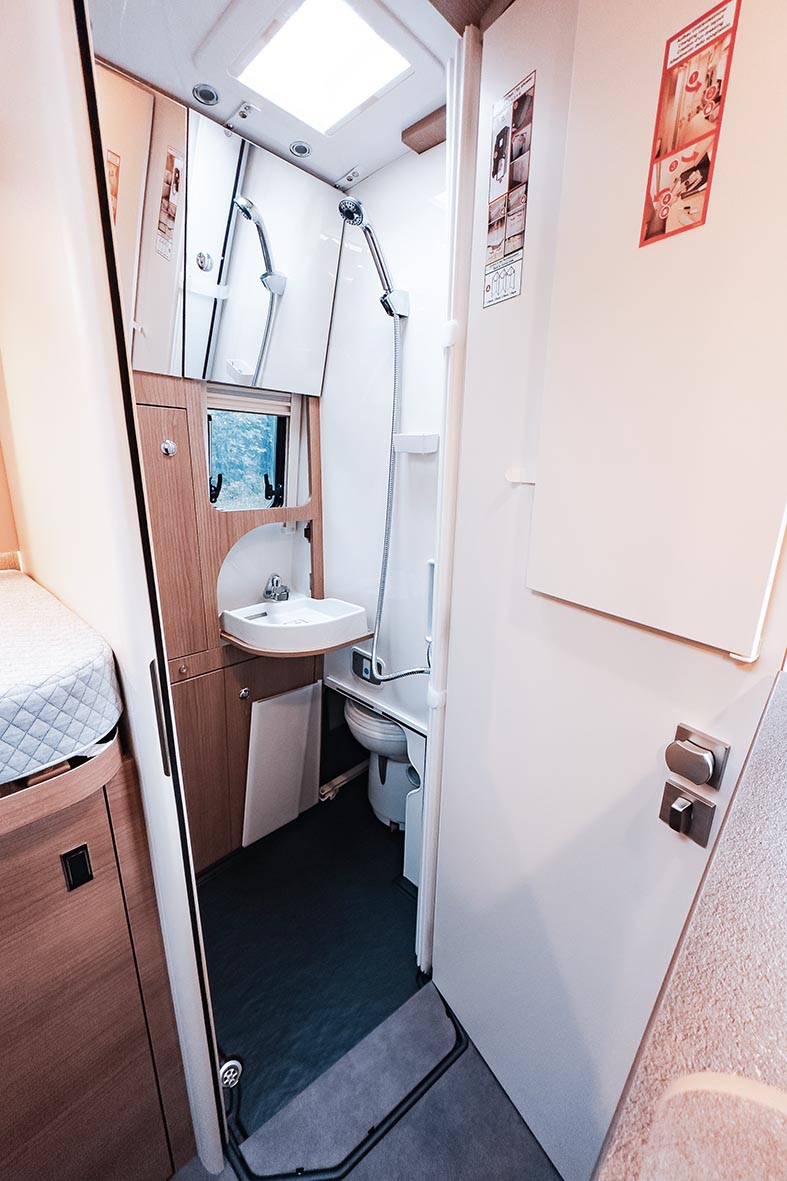 Blick in das Bad des Malibu Genius 4x4 mit Dusche, Waschbecken, Toilette und Dachfenster.