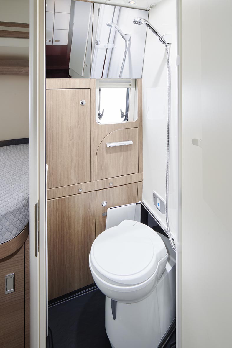 Toilette im Bad des Malibu Genius 4x4 mit Dusche, Fenster und Stauraum im Sanitärbereich.