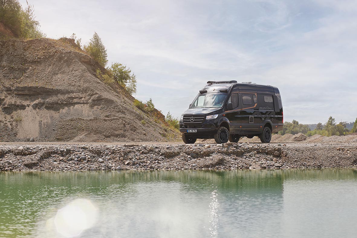 Malibu Genius Performance 4x4 auf Schottergelände an einem See als Allrad-Camper für Offroad-Reisen.